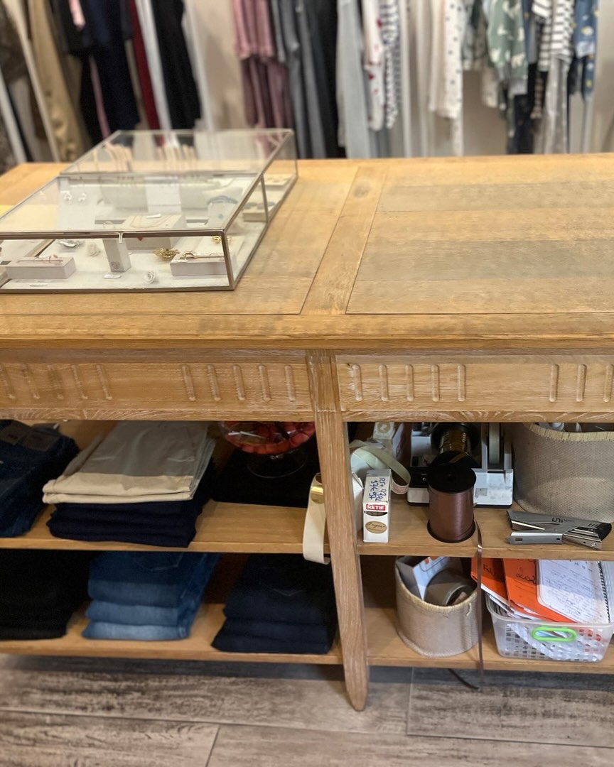 L'îlot central en chêne cérusé : vitrine de bijoux, piles de jeans et portants