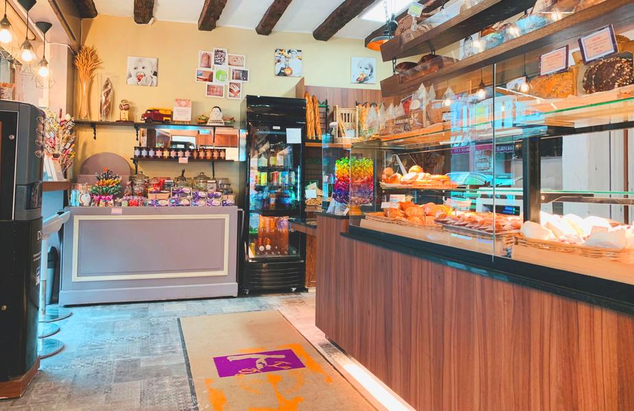 L'intérieur de la boutique : vitrines garnies de pains, viennoiseries et pâtisseries maison