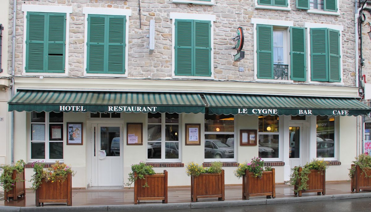 La façade du Cygne, hôtel-restaurant à la devanture verte, place du Marché