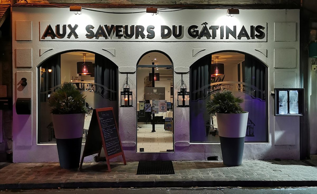 La devanture d'Aux Saveurs du Gâtinais, illuminée le soir, place du Marché