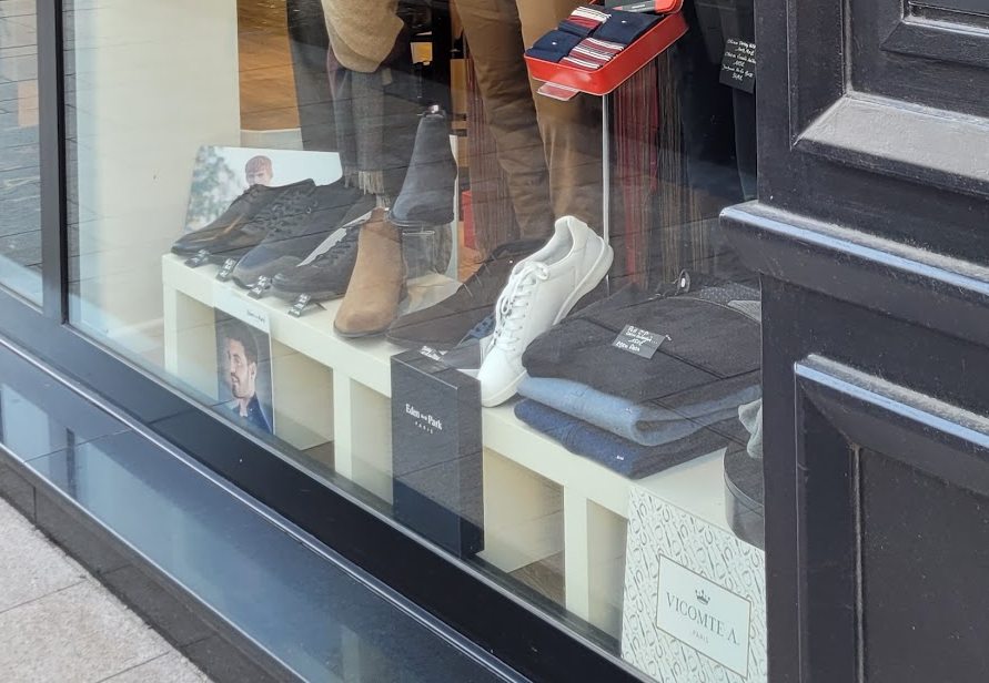 Chaussures présentées en vitrine, sur leurs présentoirs